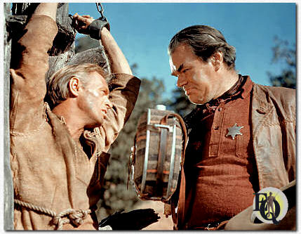 Wagon train survivors of an Apache attack entrust the sheriff's prisoner, scout Comanche Todd (Richard Widmark). Mathews is Sheriff Bull Harper in "The Last Wagon" (20th Century-Fox, Sep 21. 1956).